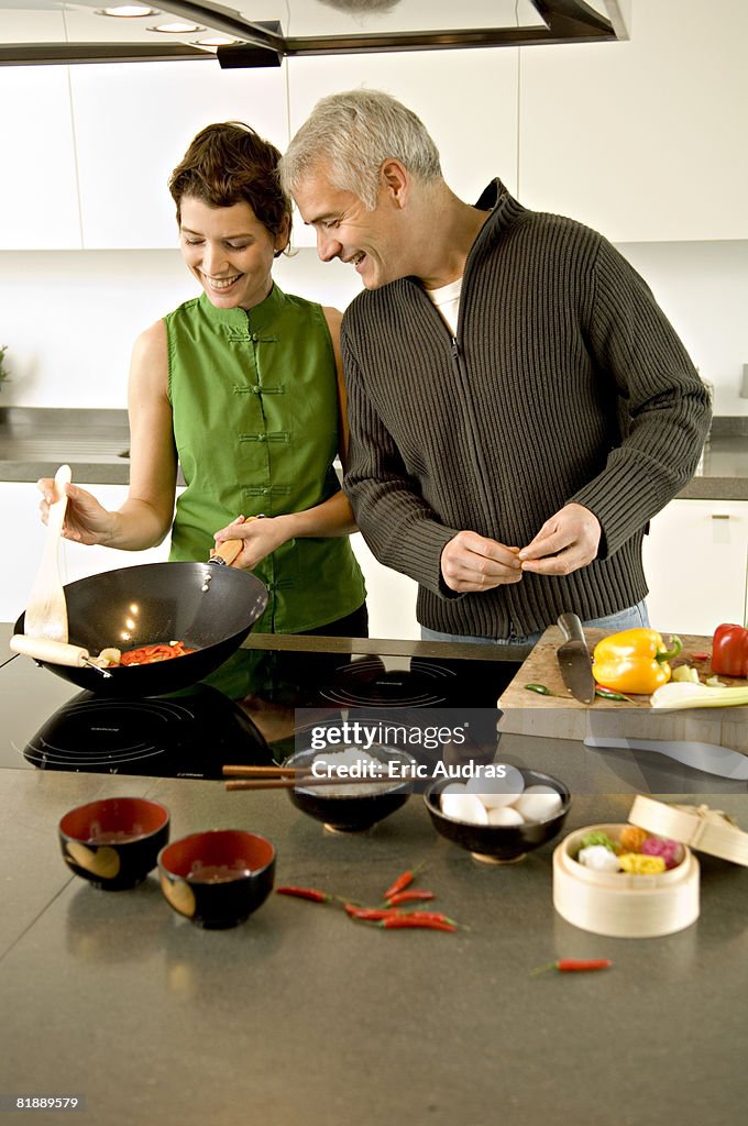 Mature man and a mid adult woman preparing food in the kitchen