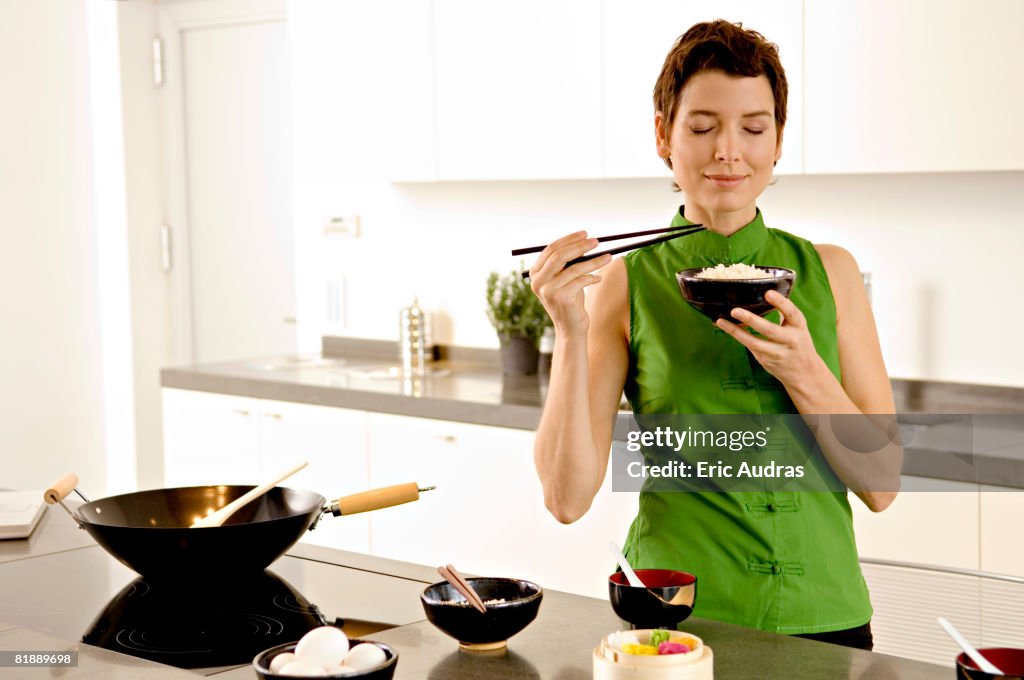 Mid adult woman smelling a bowl of rice in the kitchen