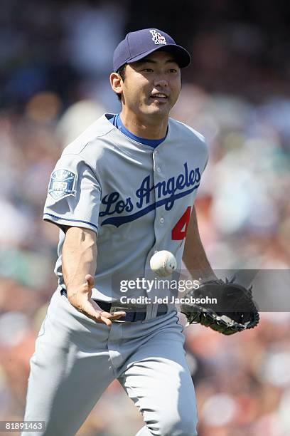 Takashi Saito of the Los Angeles Dodgers tosses the ball to first base against of the San Francisco Giants during a Major League Baseball game at...