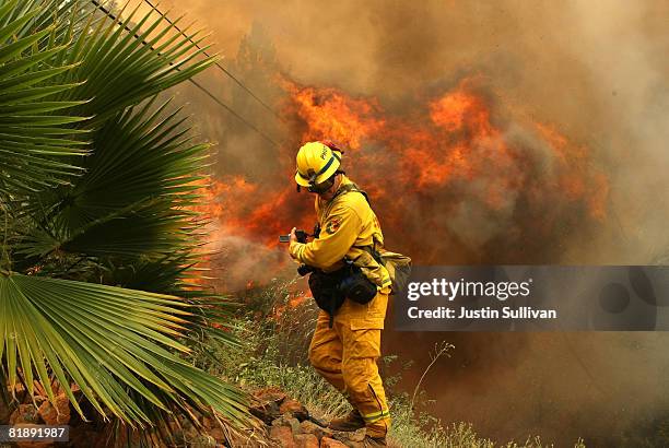 California Department of Forestry photographer shield himself from a flame as spot fire as it burns through trees and brush July 10, 2008 in Concow,...