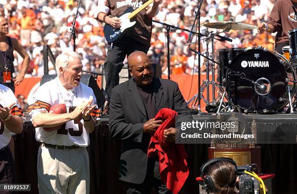 Former Cleveland Browns Frank Ryan and Jim Brown stand next to the new 1964 World Championship trophy that was unveiled prior to a game with the...