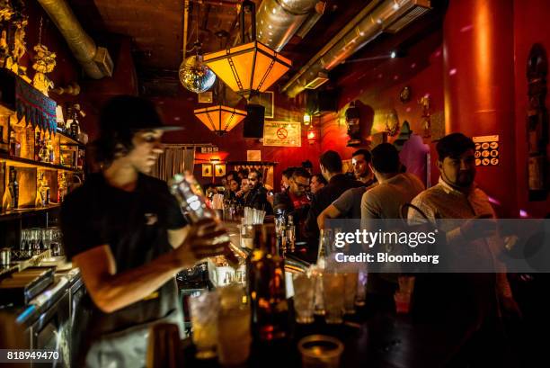 Bartender mixes cocktails at Suka Bar & Cafe in the Chacao district of Caracas, Venezuela, on Friday, July 14, 2017. In mornings and...