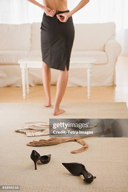 woman undressing next to clothing on floor - uitkleden stockfoto's en -beelden