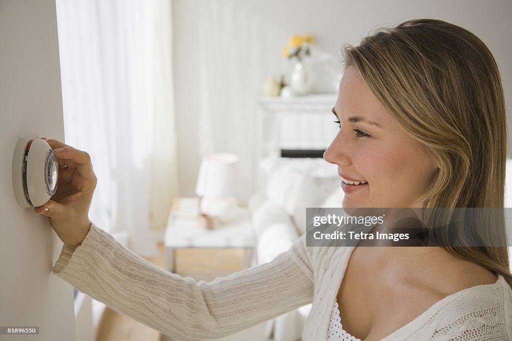 Woman adjusting thermostat