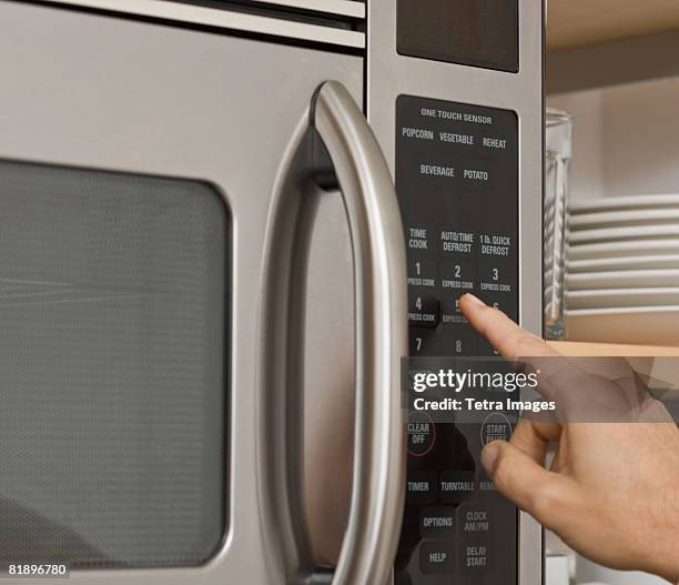 man pushing button on microwave - microwave photos et images de collection