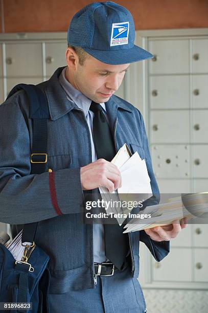 male postal worker looking at mail - postal worker stock pictures, royalty-free photos & images