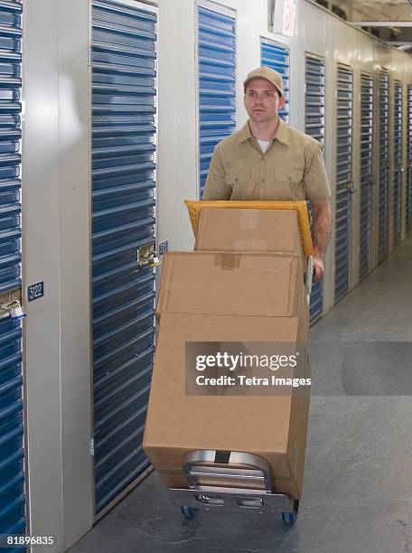 delivery man pushing stack of packages - self storage fotografías e imágenes de stock