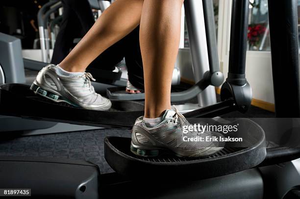 woman exercising on elliptical machine - cross trainer stock-fotos und bilder