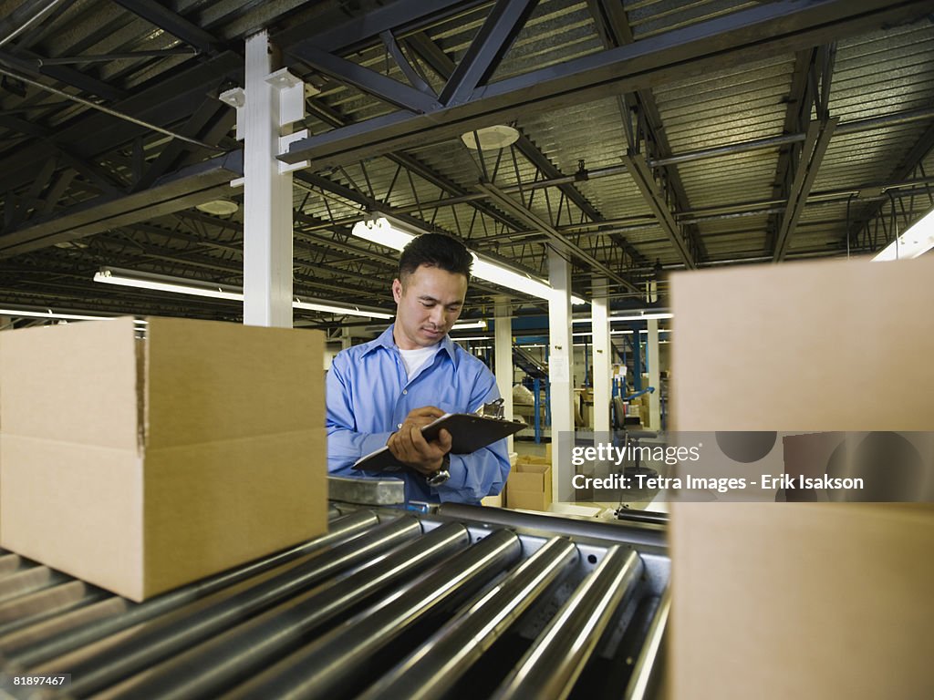 Asian male factory worker checking product