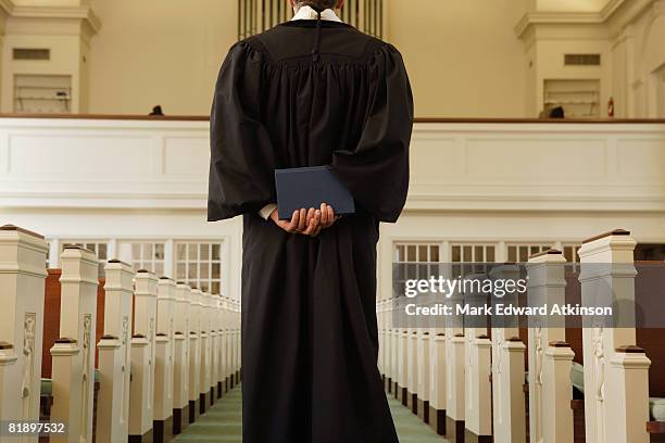 priest holding bible behind back - reverendo clerecía fotografías e imágenes de stock