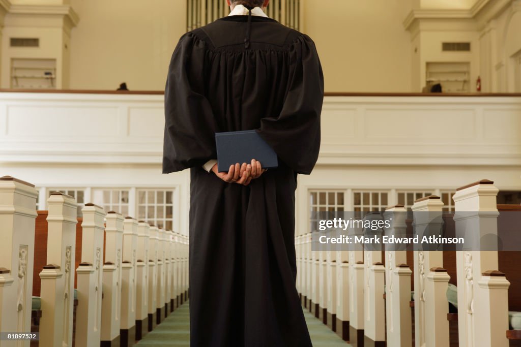 Priest holding bible behind back