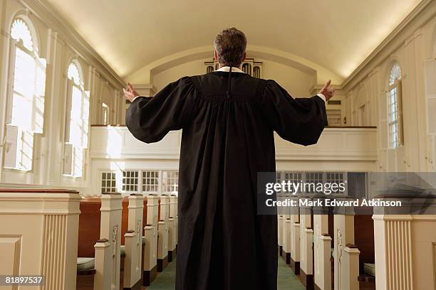 priest with arms raised in church - preacher stock-fotos und bilder