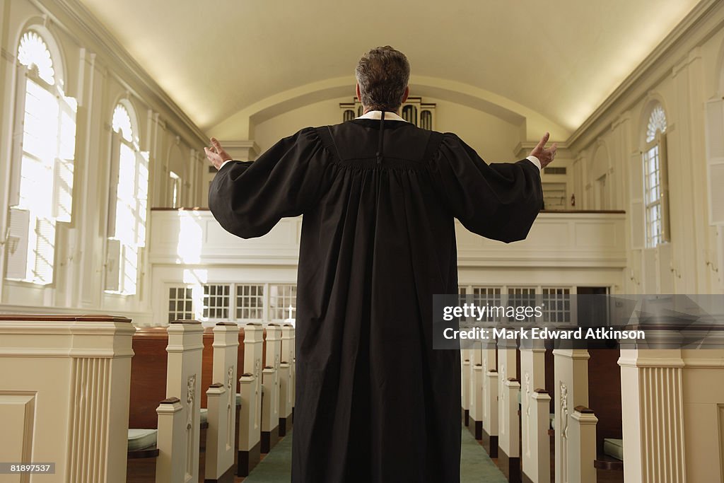 Priest with arms raised in church