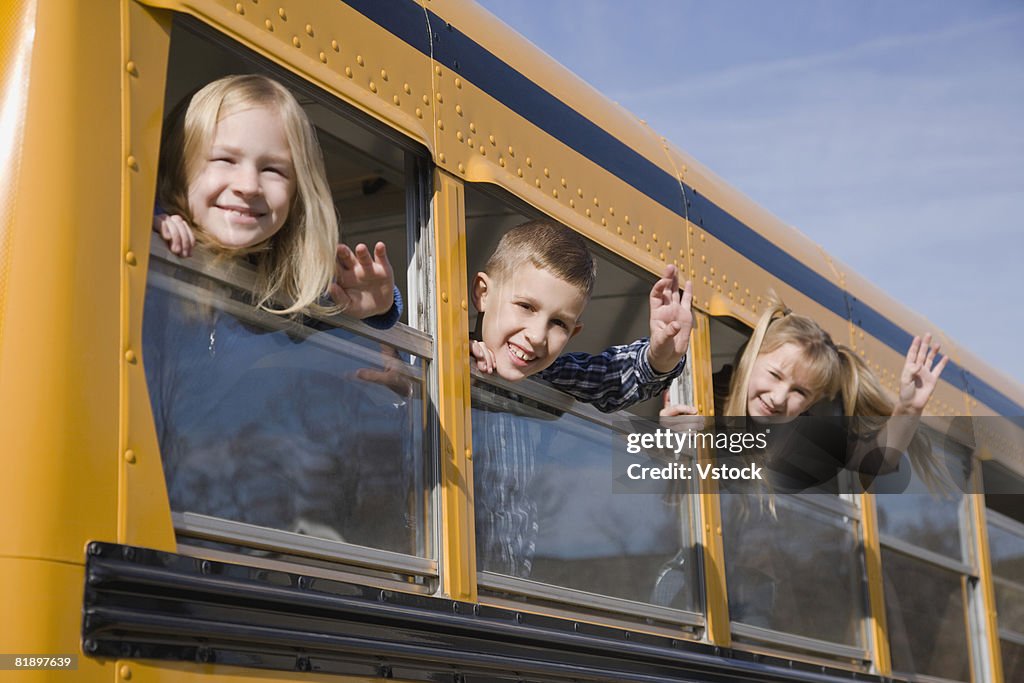 Children waving from school bus windows