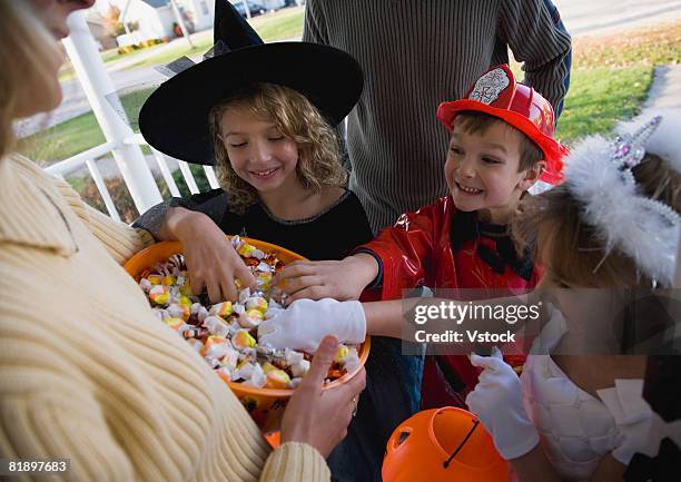 children in halloween costumes reaching into bowl of candy - bowl of candy stock-fotos und bilder