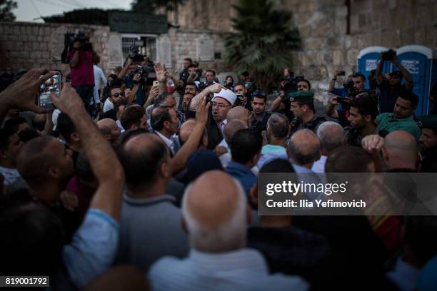 Approximately 4,000 Palestinian Muslims pray outside the entrance to the old city of Jerusalem as it is partially blocked by Israeli Police on July...