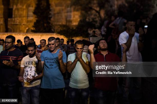 Approximately 4,000 Palestinian Muslims pray outside the entrance to the old city of Jerusalem as it is partially blocked by Israeli Police on July...