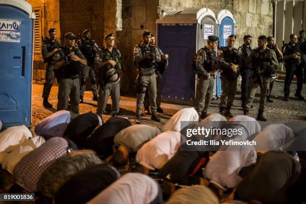 Approximately 4,000 Palestinian Muslims pray outside the entrance to the old city of Jerusalem as it is partially blocked by Israeli Police on July...