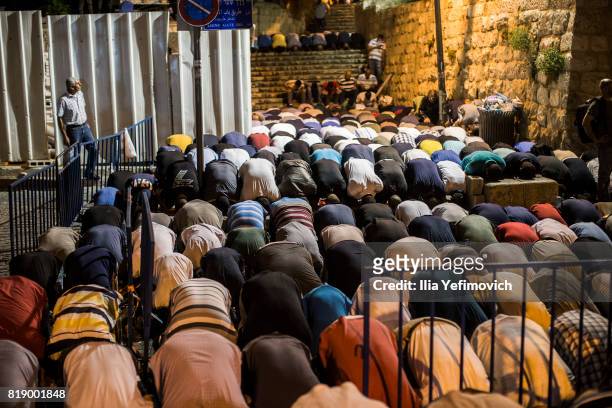 Approximately 4,000 Palestinian Muslims pray outside the entrance to the old city of Jerusalem as it is partially blocked by Israeli Police on July...