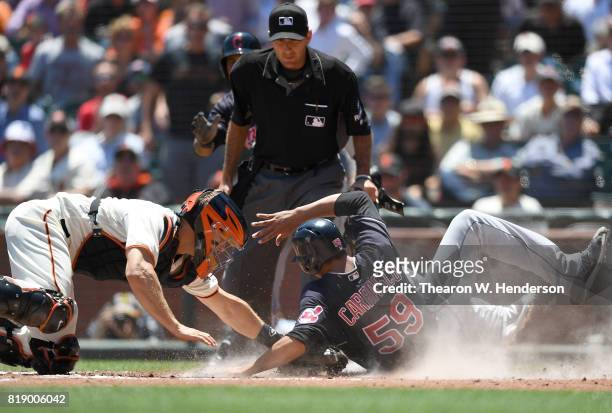 Carlos Carrasco of the Cleveland Indians scores sliding around the tag of Nick Hundley of the San Francisco Giants in the top of the third inning at...