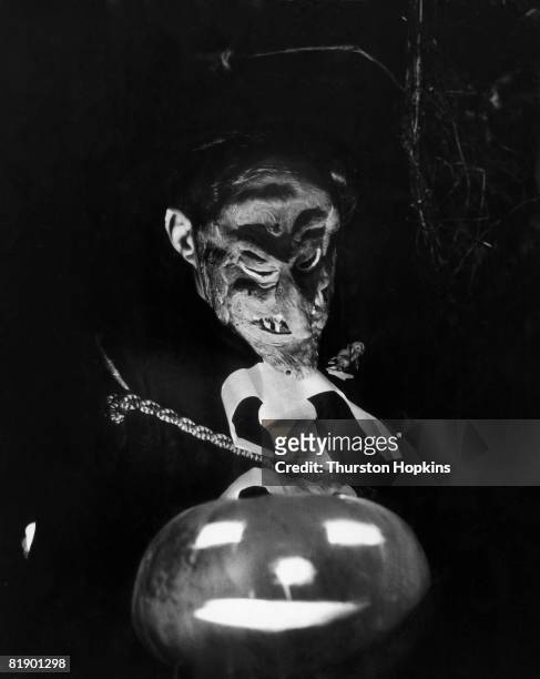 Masked guest with a pumpkin at a fancy dress halloween party given to welcome American actress Barbara Bates to Britain, 31st October 1956. Original...