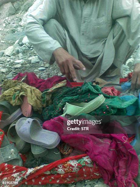 In this photograph taken on July 10, 2008 an Afghan man shows the media women and children's clothes in Deh Bala village in Ningarhar province....