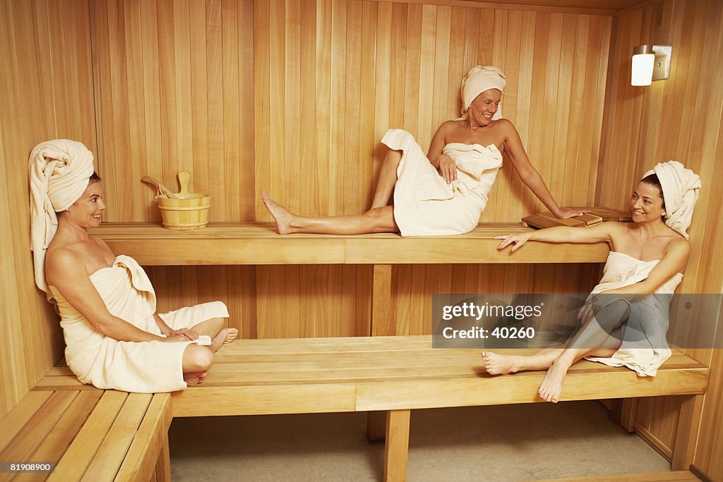 Three Mature Women Wearing Towels Sitting In A Sauna High-Res