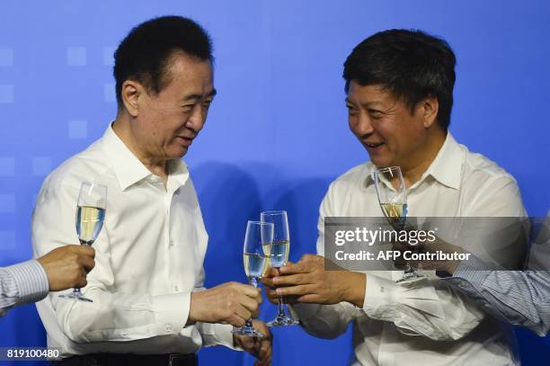 This picture taken on on July 19, 2017 shows Chairman of China's Wanda Group Wang Jianlin sharing a toast with chairman of Sunac China Holdings...