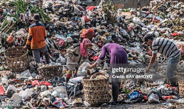 Scavengers collect valuable items to resale at a garbage dump in Jakarta on July 20, 2017.