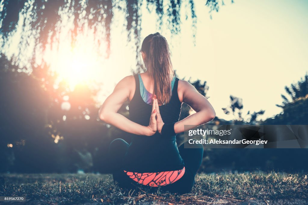 Female Doing Meditation Practice Against the Sunset in Nature