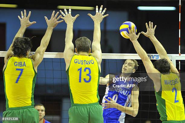 France's Guillaume Samica 's spike is blocked by Brazil's Giba, Gustavo and Marcelinho during their Volleyball World League fifth round match in Belo...