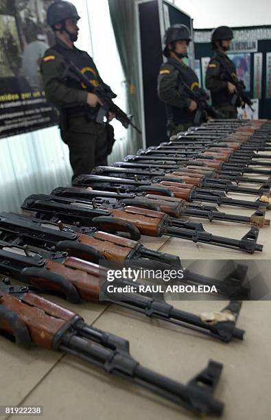 Colombian policemen stand before an arsenal seized to "La Oficina" rigth-wing paramilitary group on July 13 in Medellin, Antioquia Department,...