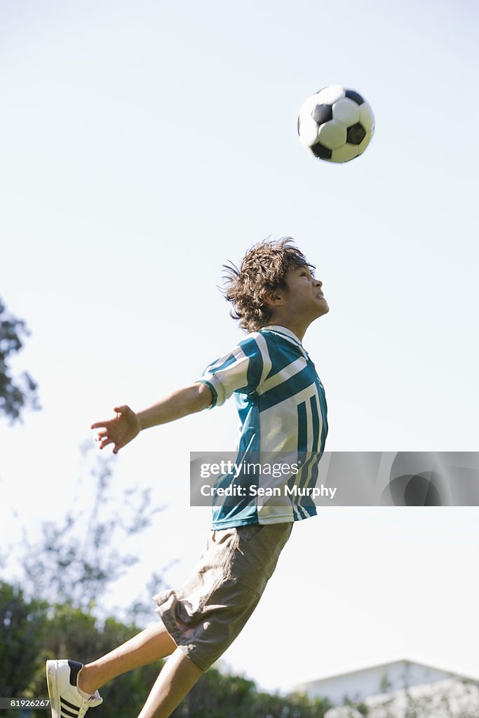 Young boy en dirección una pelota de fútbol