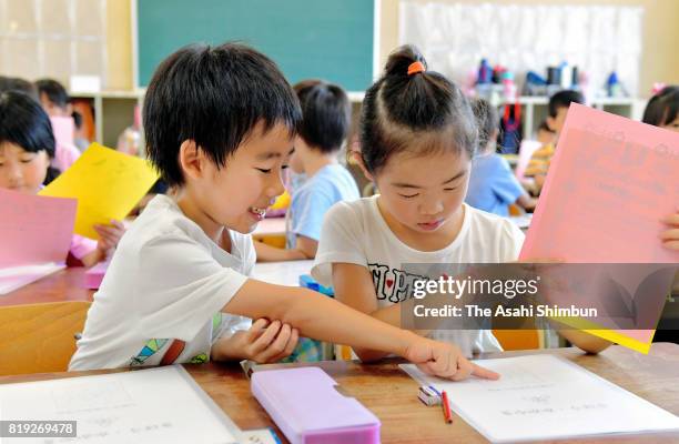 Children smile as they receive their first term school report on July 20, 2017 in Osaka, Japan. Most schools in Kansai region finish their first term...