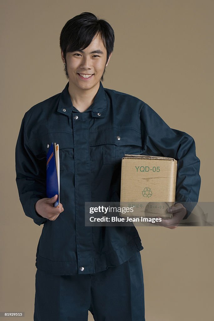 Chinese courier holding box and packages, portrait