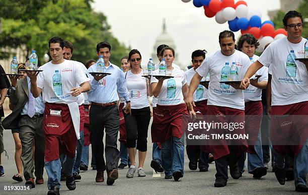 Participants carry a tray with a bottle of water and a glass of champgne balanced upon it during The Brasserie Les Halles 34th Annual Waiter and...