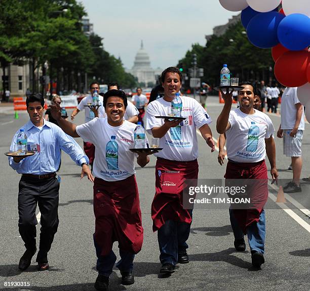 Participants carry a tray with a bottle of water and a glass of champgne balanced upon it during The Brasserie Les Halles 34th Annual Waiter and...