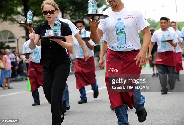 Participants carry a tray with a bottle of water and a glass of champgne balanced upon it during The Brasserie Les Halles 34th Annual Waiter and...