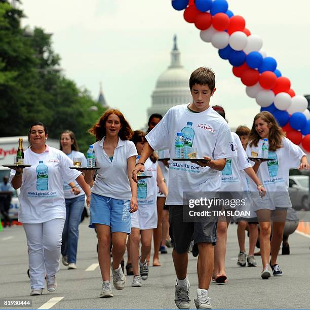 Participants carry a tray with a bottle of water and a glass of champgne balanced upon it during The Brasserie Les Halles 34th Annual Waiter and...