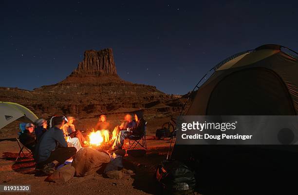 Mountain bikers cook dinner under a sky laiden sky on a full moon night at the Airport campsite on the White Rim Trail on October 25, 2007 in...