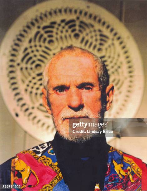 View of American psychologist Dr Timothy Leary , wearing a dark scarf beneath a colorful vest, as he poses in front of a mandala at the entrance to...