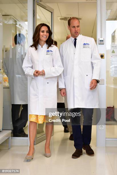 Prince William, Duke of Cambridge and Catherine, Duchess of Cambridge don white lab coats during their visit to the German Cancer Research Institute...