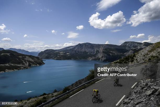Great Britain's Christopher Froome , wearing the overall leader's yellow jersey, rides past a lake during the 179,5 km eighteenth stage of the 104th...