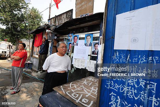 Residents stand in front of a home plastered with portraits of China's top communist leaders in an attempt to fight off a government eviction as a...