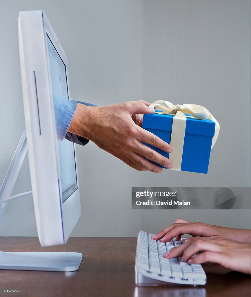 Hands typing on keyboard while a gift appears from a computer screen