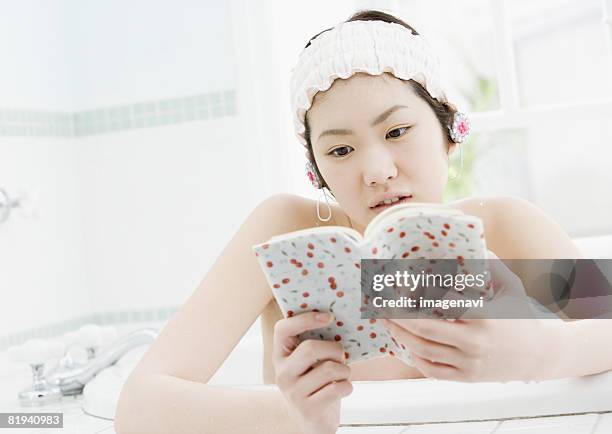 woman reading a book in bathtub - japanese women bath stock pictures, royalty-free photos & images