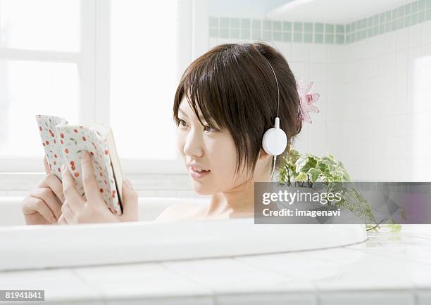 woman reading a book in bathtub - japanese women bath stock pictures, royalty-free photos & images