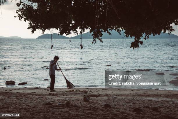 silhouettes of man sweeping on the beach - sweeping landscape stock pictures, royalty-free photos & images