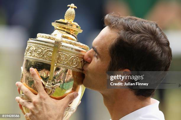 Roger Federer of Switzerland kisses the trophy as he celebrates victory after the Gentlemen's Singles final against Marin Cilic of Croatia on day...