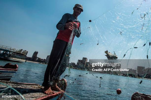 An Egyptian fisherman pulls his fishing net out of the River Nile in Cairo on July 20, 2017. / AFP PHOTO / KHALED DESOUKI